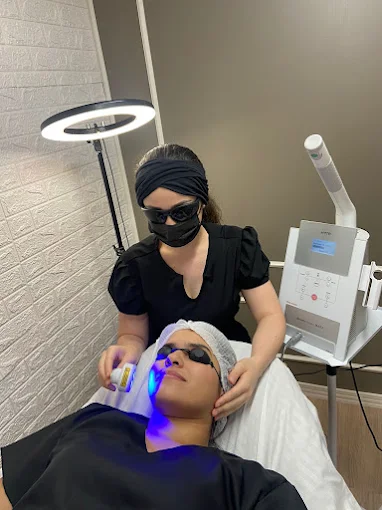 Amanda Custódio realizando um atendimento facial com aparelho de LED